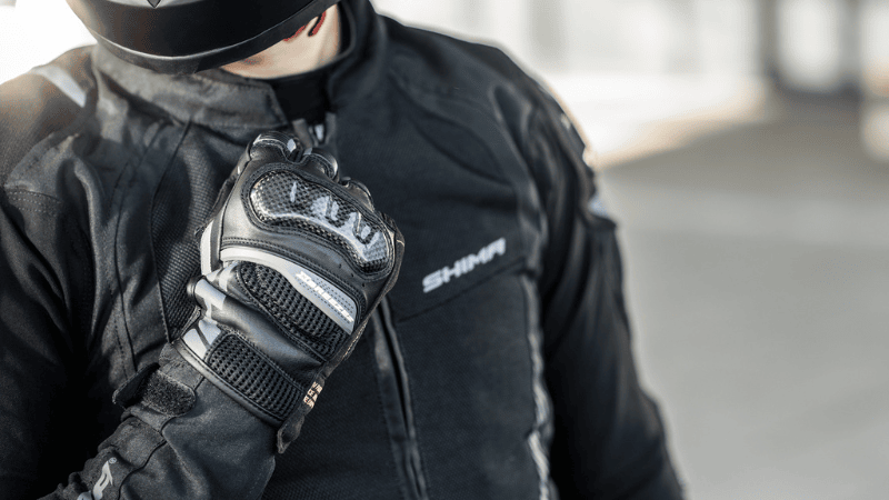 Jakie rękawice motocyklowe? Czarne rękawice motocyklowe Shima X-Breeze-2 na tle kurtki Shima